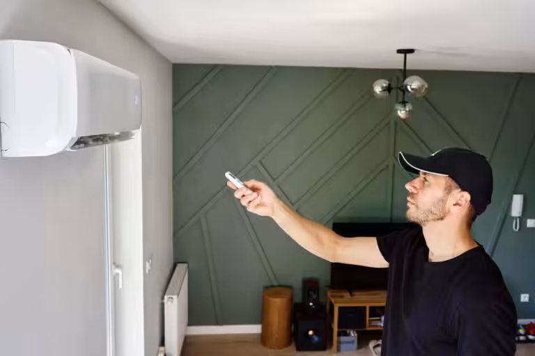 Man adjusting air conditioner with remote