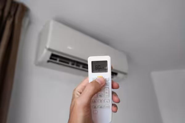 Hand holding remote towards air conditioner
