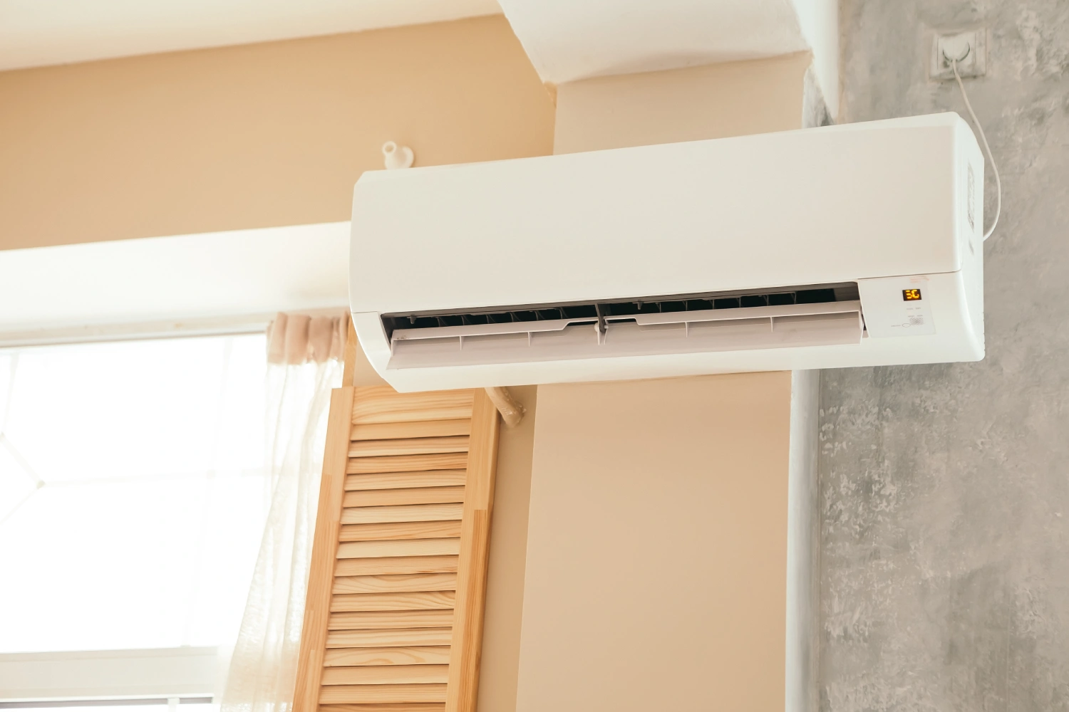 Wall-mounted air conditioner above window indoors