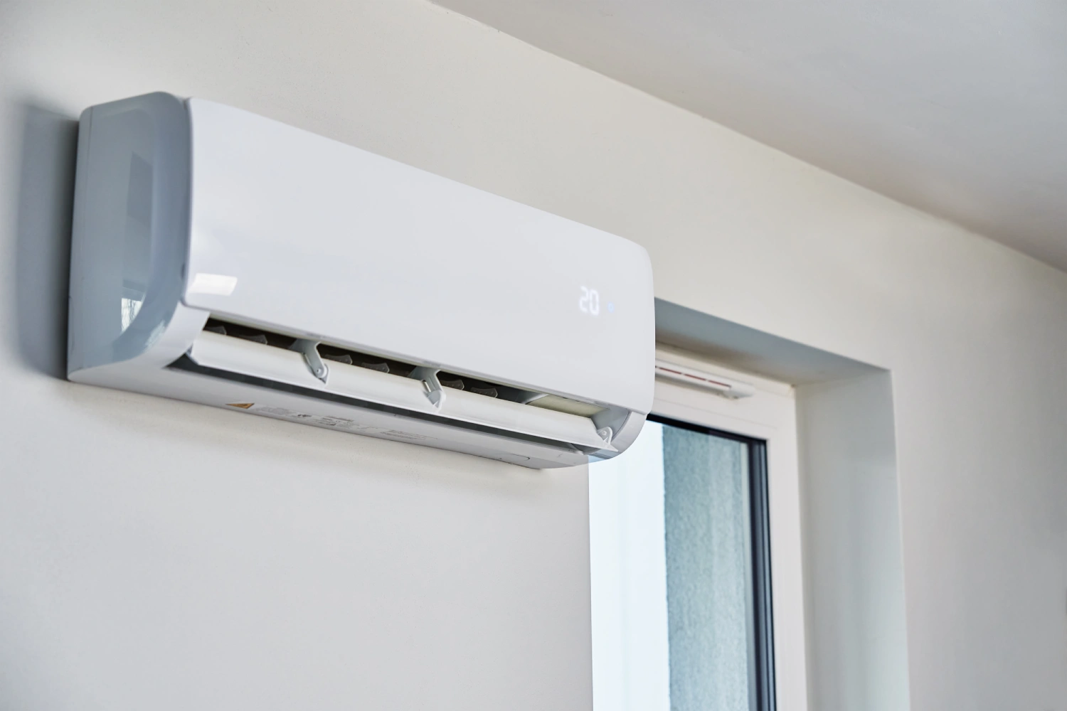 Wall-mounted air conditioner unit near window